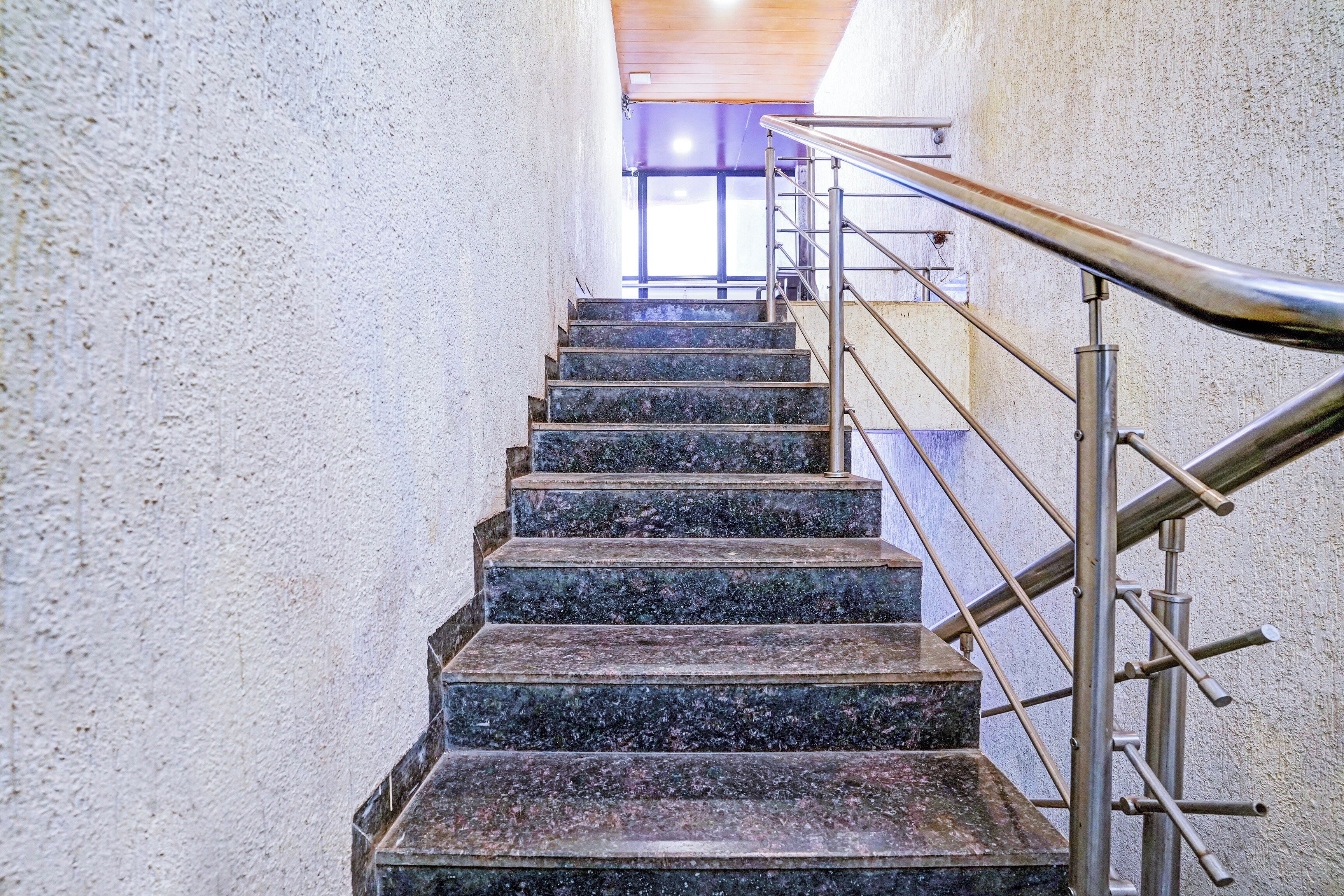 Een trap met metalen leuningen en een handrail, die naar een hoger gelegen verdieping leidt.