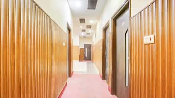 Un pasillo con paneles de madera a ambos lados, alfombra roja y puertas con números de habitación.