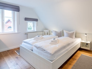 Ein Schlafzimmer mit einem großen Bett, zwei Nachttischen, einem Fenster und einer Heizung.