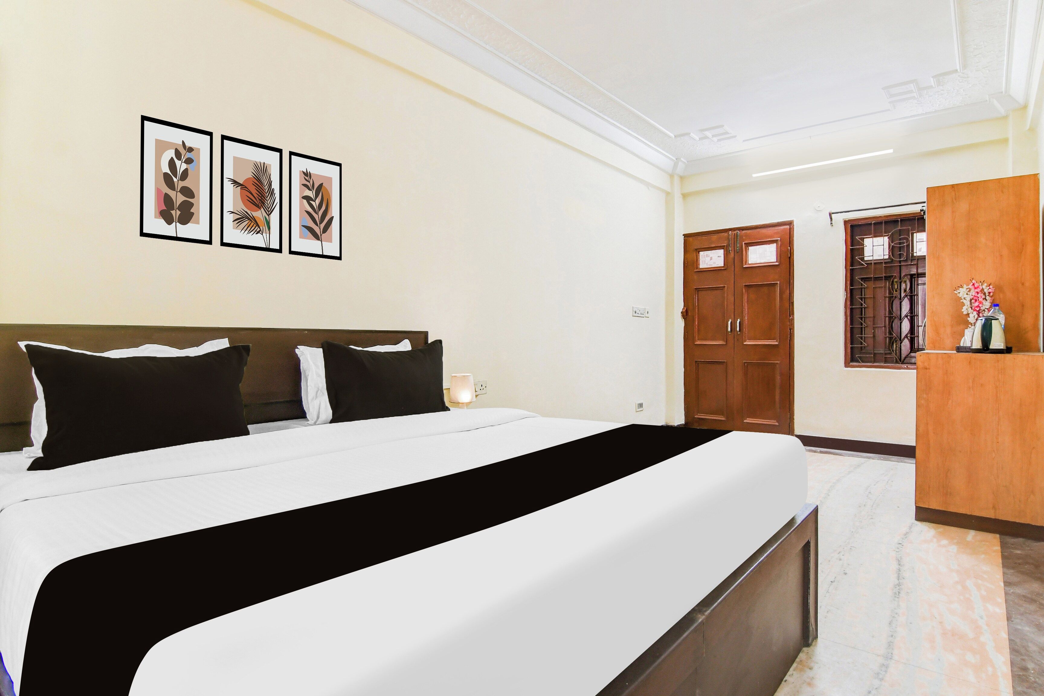 Una habitación de hotel con una cama, una mesita de noche, una lámpara, un armario y cuadros en la pared.