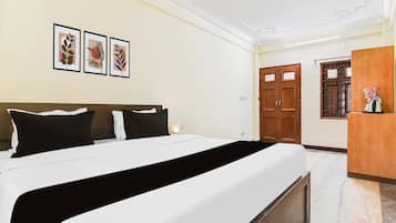 Una habitación de hotel con una cama, una mesita de noche, una lámpara, un armario y cuadros en la pared.