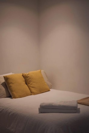 A neatly made bed with a folded white towel and two striped pillows. - Luxury CBD Escape | Pool, Sauna & City Views (Melbourne)