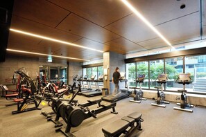 A gym with cardio machines, weightlifting equipment, and treadmills. - Luxury CBD Escape | Pool, Sauna & City Views (Melbourne)