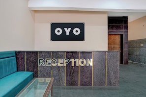 Un área de recepción con un letrero que dice 'OYO' y un mostrador de recepción.