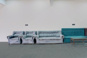 A room with a grey sofa, a teal sofa, and a small table. - Hotel O Shiv Palace (Agra)