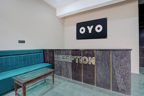 A reception area with a teal sofa, a reception desk, and a sign that reads 'OYO RECEPTION'. - Hotel O Shiv Palace (Agra)