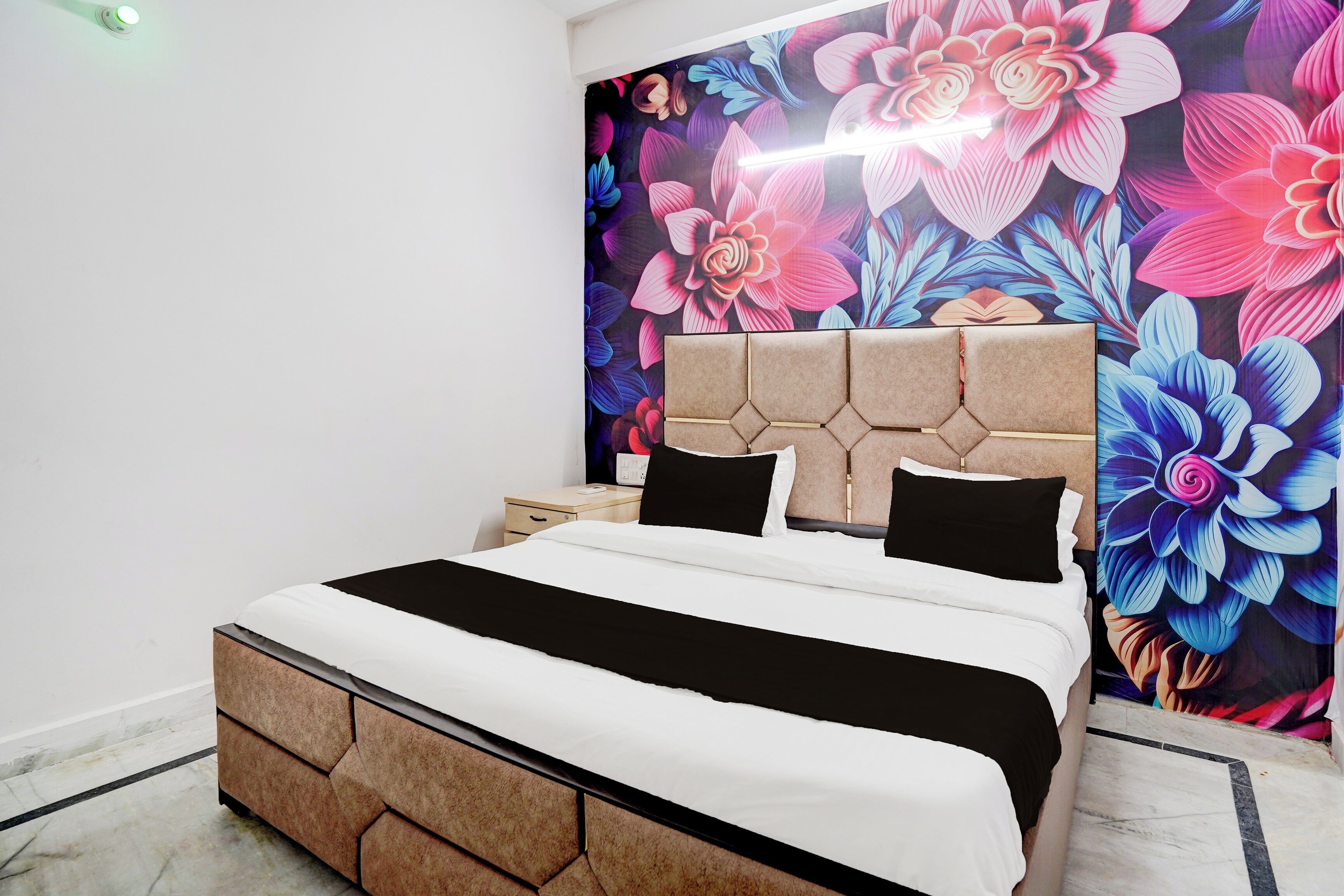 A bed with a headboard, a bedside table, and a wall with a floral mural.