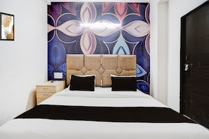 A hotel room with a bed, a headboard, a nightstand, and a door. - Hotel O R K HOTEL (Agra)