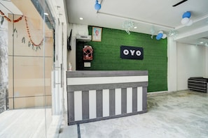 A reception area with a green wall, a sign reading 'OYO', and a wooden reception desk. - Hotel O R K HOTEL (Fatehabad)