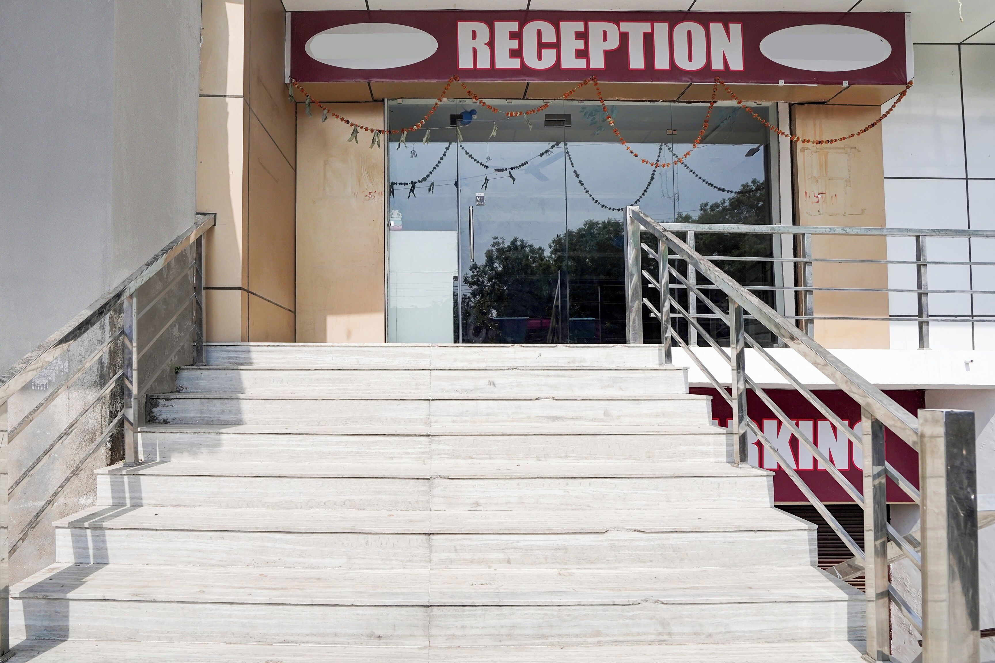 A reception area with a staircase leading up to a door, a sign above the door, and a railing on the stairs.