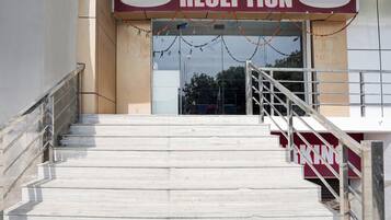 A reception area with a staircase leading up to a door, a sign above the door, and a railing on the stairs.