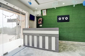 A reception area with a green wall, a sign reading 'OYO', and a small shrine. - Hotel O R K HOTEL (Agra)