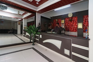 A reception desk with a clock, a small Christmas tree, and a plant. - Hotel O Gayatri Palace (Agra)