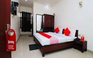 A hotel room with a bed, a nightstand, a wardrobe, and a door with a 'Please do not disturb' sign. - Hotel O Gayatri Palace (Agra)
