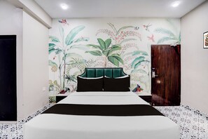 Ein Schlafzimmer mit einem Bett, einem Holzschrank und einer Wand mit Wandmalereien von tropischen Pflanzen und Vögeln.