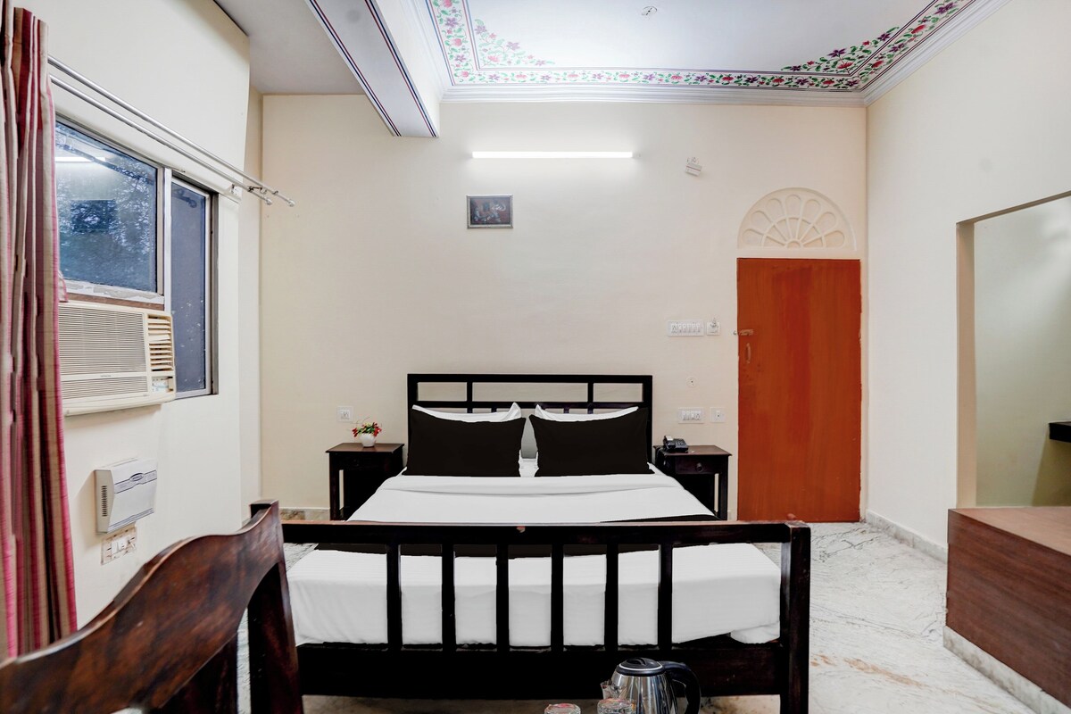 Ein Hotelzimmer mit Bett, Nachttischen, einem Fenster, einer Tür und einem Spiegel.