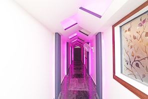 A hallway with a modern design, featuring a staircase, a fan, and a framed artwork on the wall. - HOTEL O 03 TOWN HOUSE Shaheed Captain (Agra)