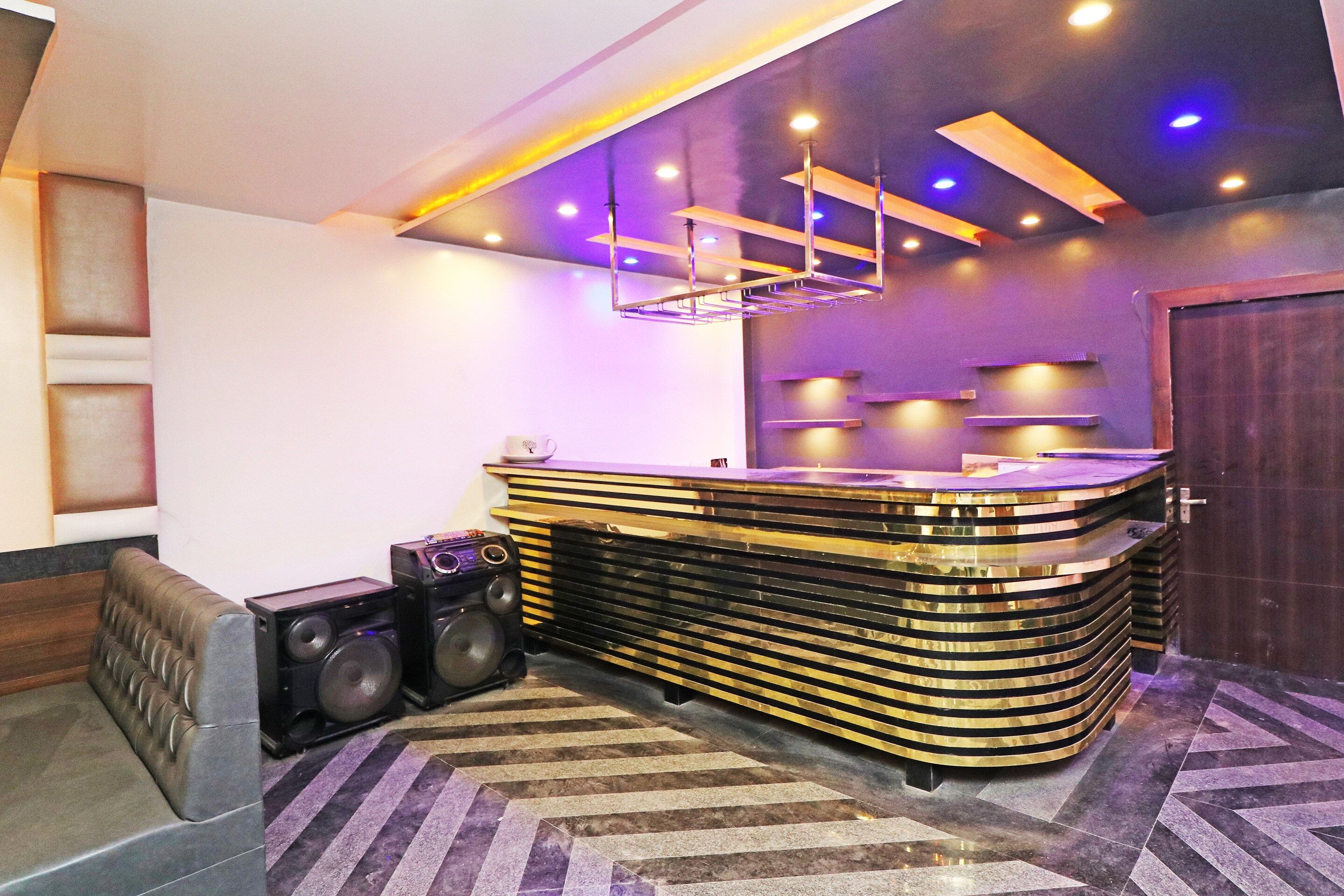 Un área de bar moderna con una barra curva, altavoces y un suelo estampado.