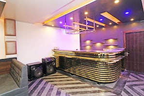 A modern bar area with a curved counter, speakers, and a patterned floor. - HOTEL O 03 TOWN HOUSE Shaheed Captain (Agra)