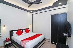 Una habitación de hotel con cama, mesita de noche, lámpara y armario.
