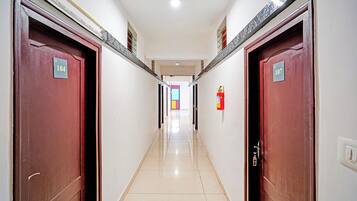 Un pasillo con puertas numeradas 104 y 107, un extintor en la pared y suelo de baldosas.