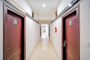 A corridor with doors numbered 104 and 107, a fire extinguisher on the wall, and a tiled floor. - Townhouse Madikeri Fort (Madikeri)