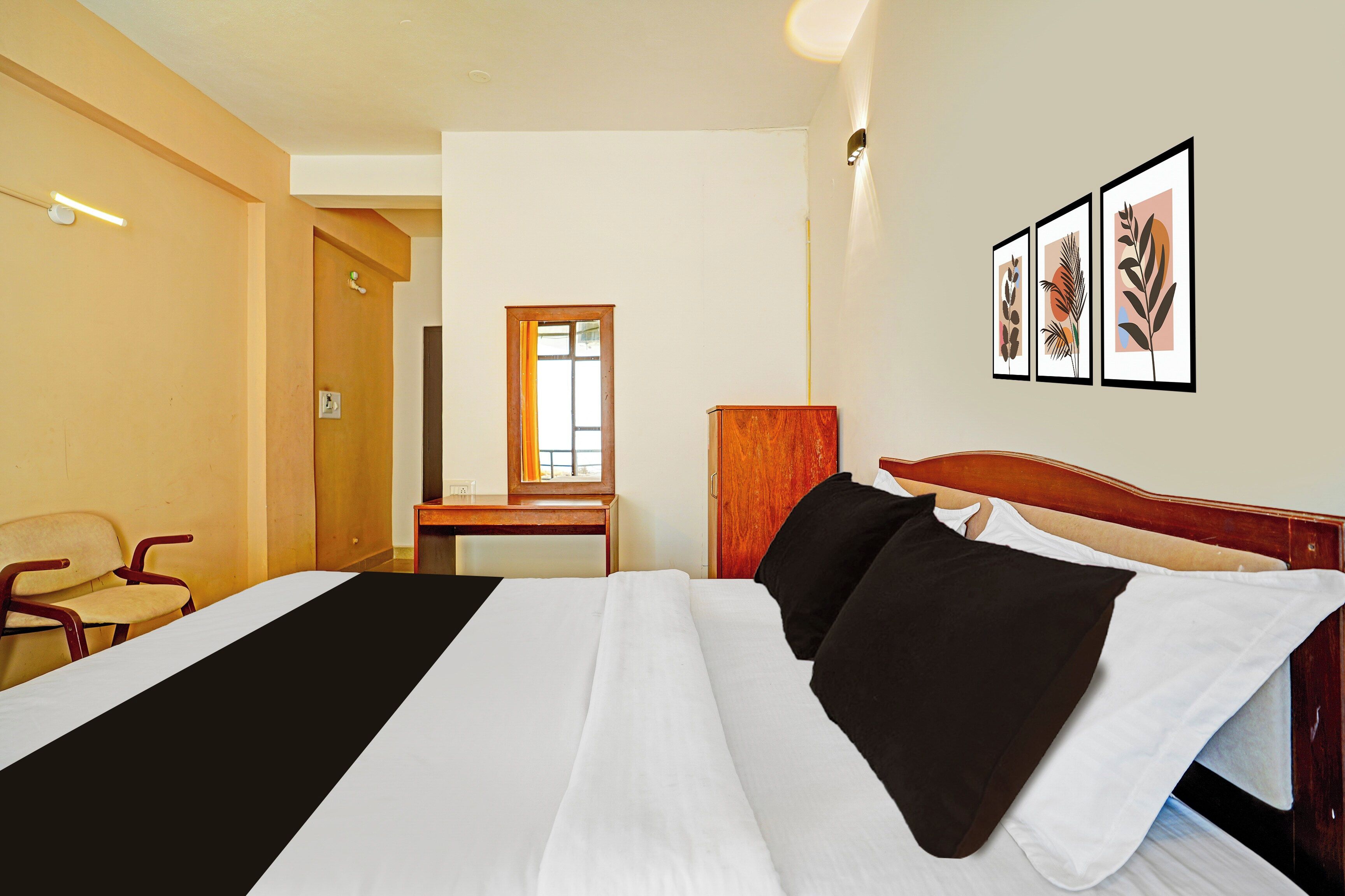 A hotel room with a bed, a chair, a desk, and a door.