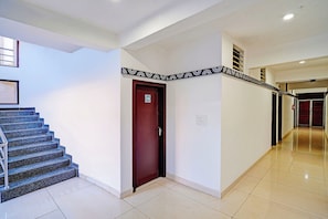 A hotel corridor with a staircase, a door with a number sign, and a patterned border on the wall. - Townhouse Madikeri Fort (Madikeri)