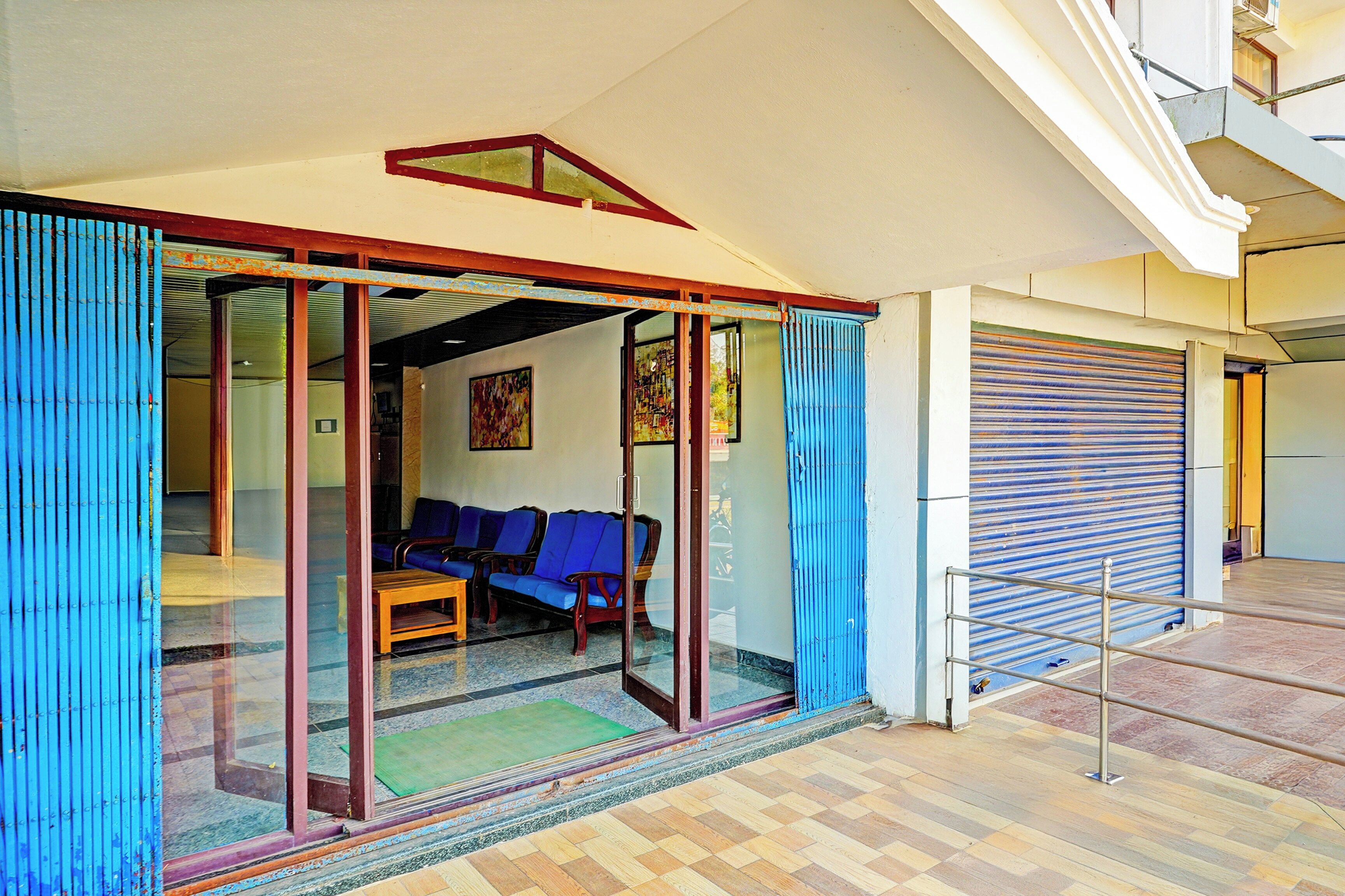 Una habitación con puerta de vidrio, sofá azul y mesa de madera.