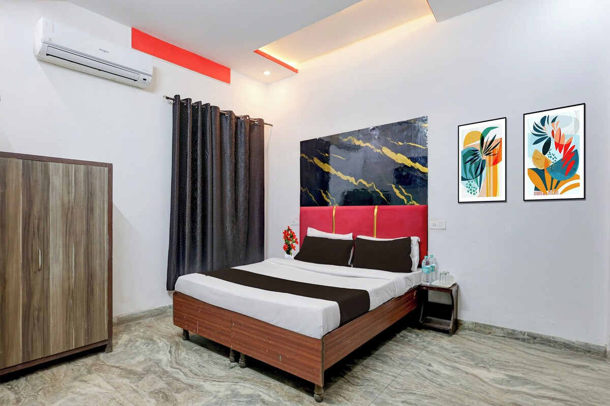 A modern hotel room with a bed, a wardrobe, a nightstand, and two abstract paintings on the wall.