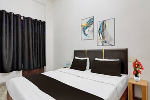 A hotel room with a bed, a nightstand, a vase with flowers, and two abstract paintings on the wall. - Hotel O by OYO Dariya Railway Station (Chandigarh)
