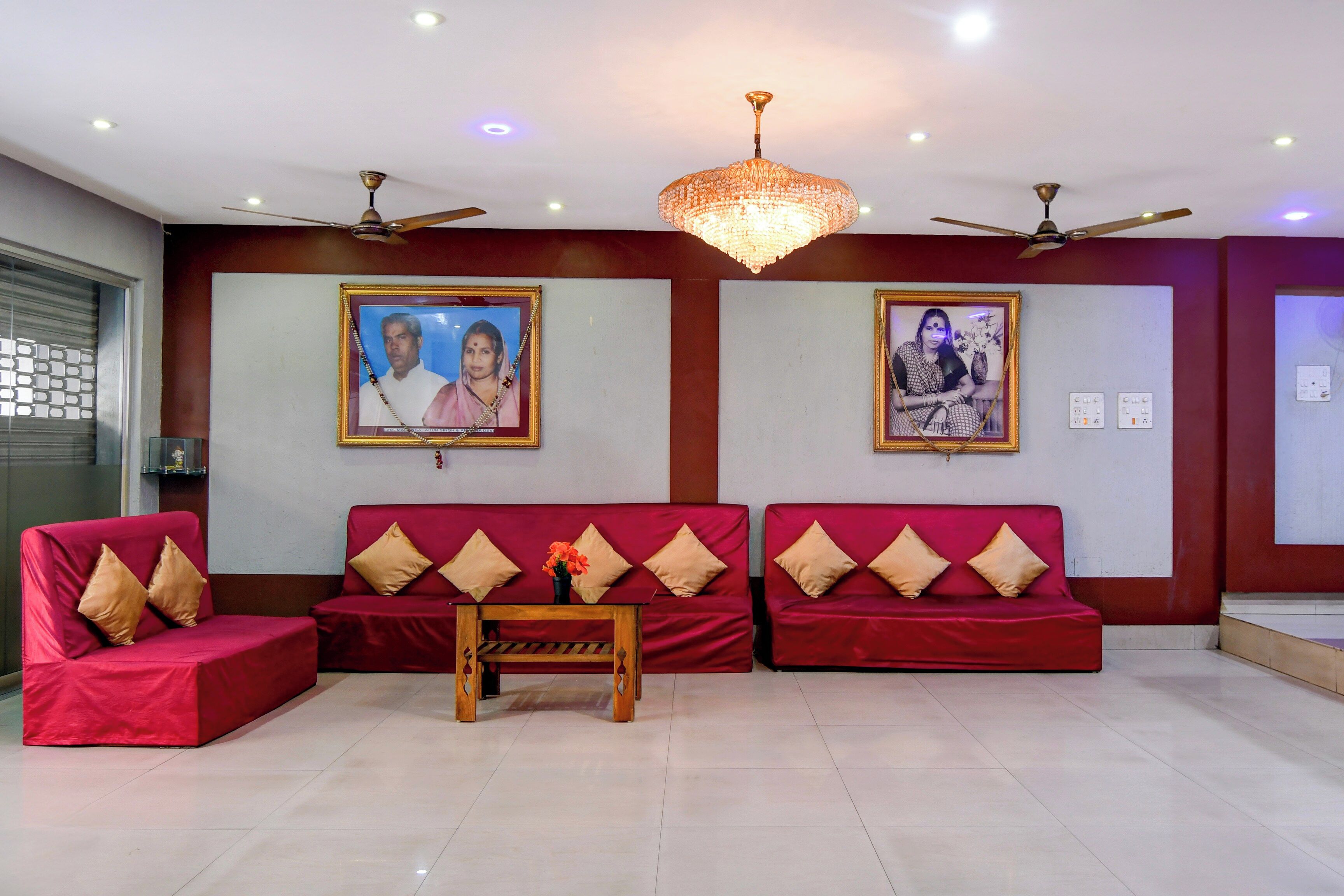 A reception area with red sofas, a wooden coffee table, and two ceiling fans.