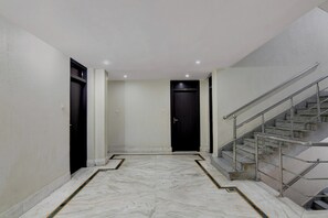 A hallway with a marble floor, a black door at the end, and a staircase with metal railings. - Super Collection O Sakchi Crossway (Jamshedpur)