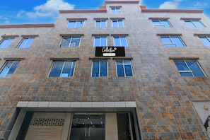 Un edificio de varios pisos con fachada de piedra, ventanas grandes y un letrero que indica que es un conjunto de departamentos con servicios de empresa.