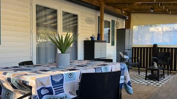 Eine Terrasses mit Tisch, der mit einer Patchwork-Tischdecke bedeckt ist, einem Blumentopf und einem Holzboden.