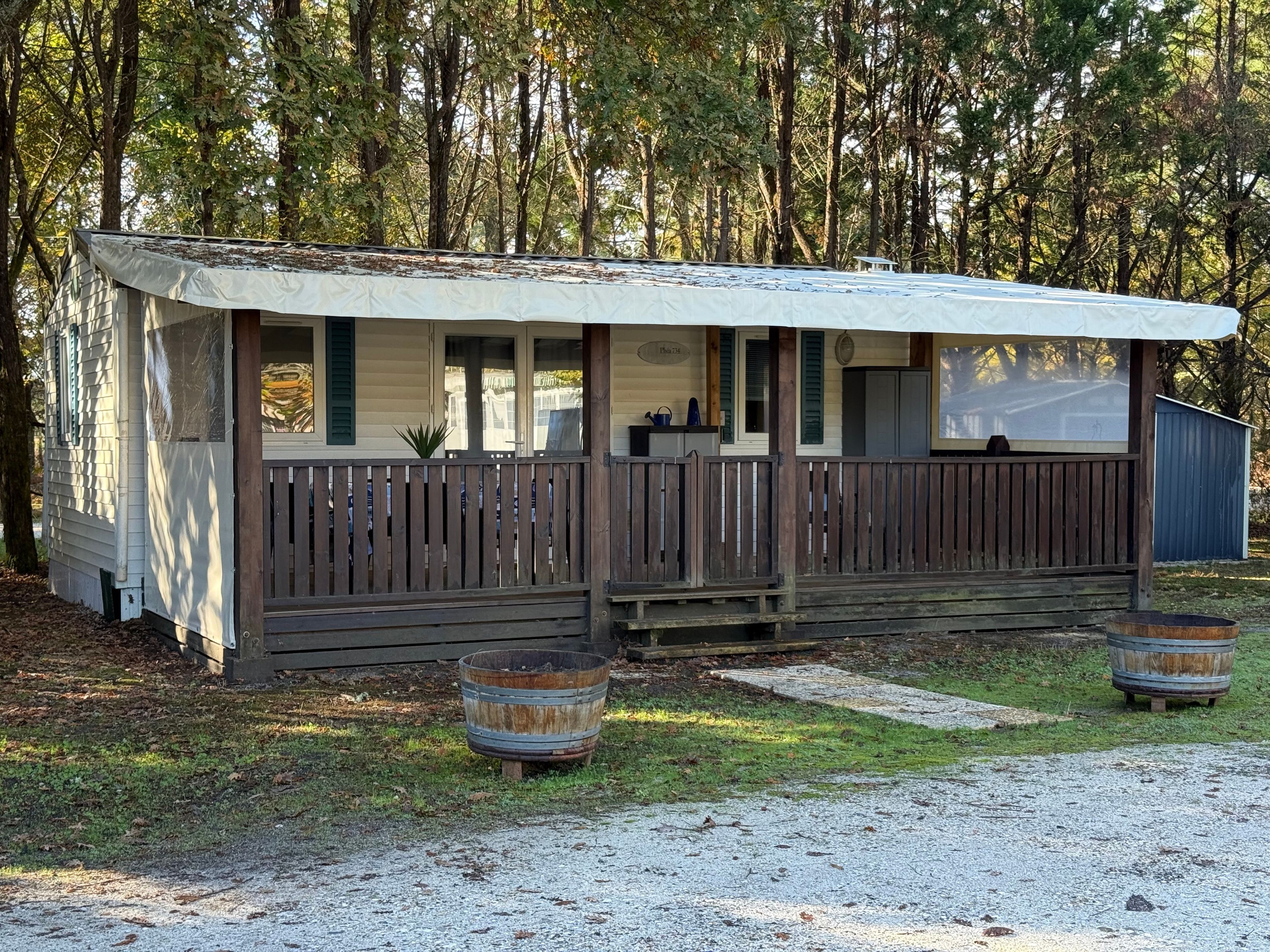 Een gelijkvloerse stacaravan met een overdekte veranda, een omheinde tuin en een grindpad.