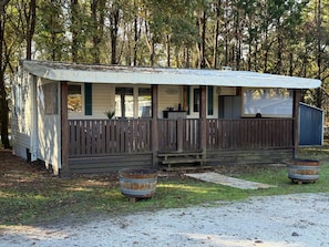 Een gelijkvloerse stacaravan met een overdekte veranda, een omheinde tuin en een grindpad.