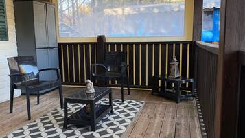 Un espacio de estar al aire libre cubierto con dos sillas, una mesa y un farol decorativo.