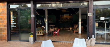 Een café met terras, een gevel van baksteen en een bord waarop de openingstijden staan.