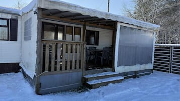 Une petite maison mobile d’un seul étage, dotée d’un porche et d’un espace extérieur aménagé et abrité.