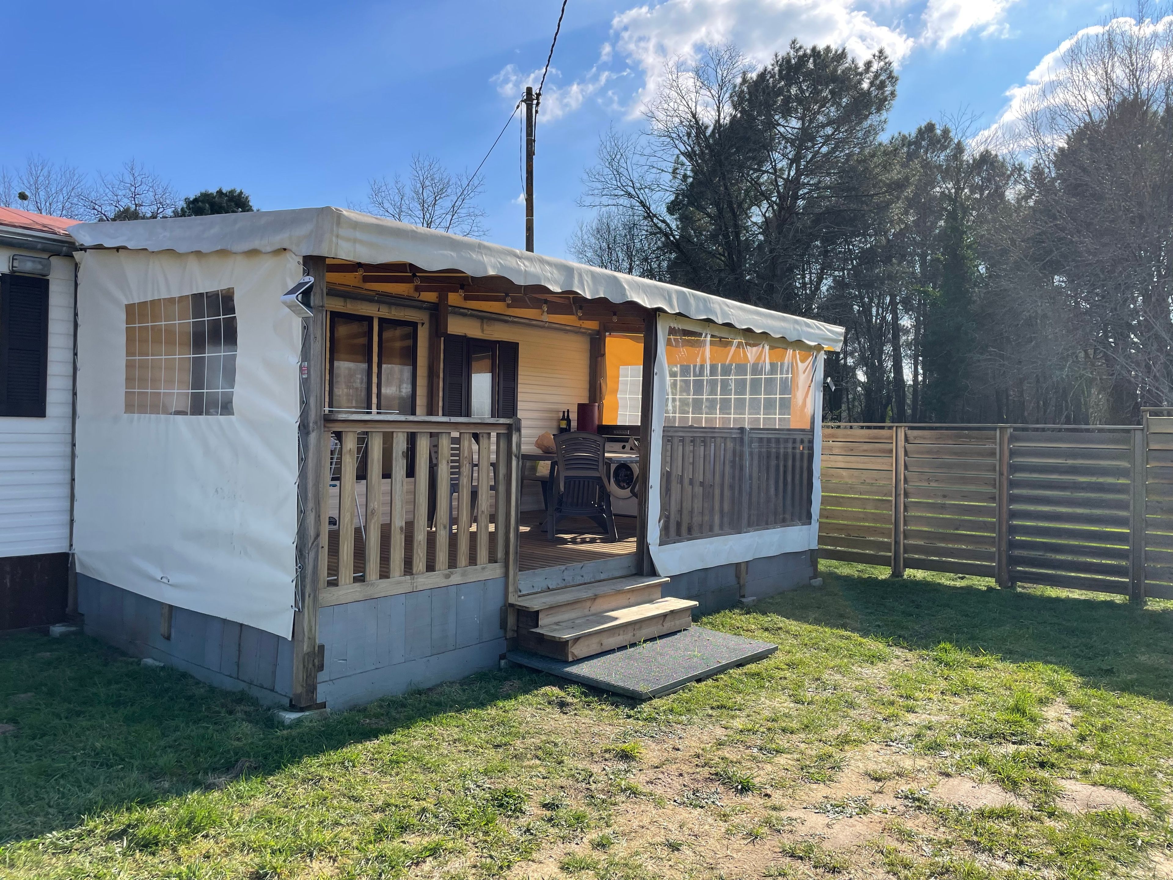 A mobile home with a porch and a small outdoor seating area.