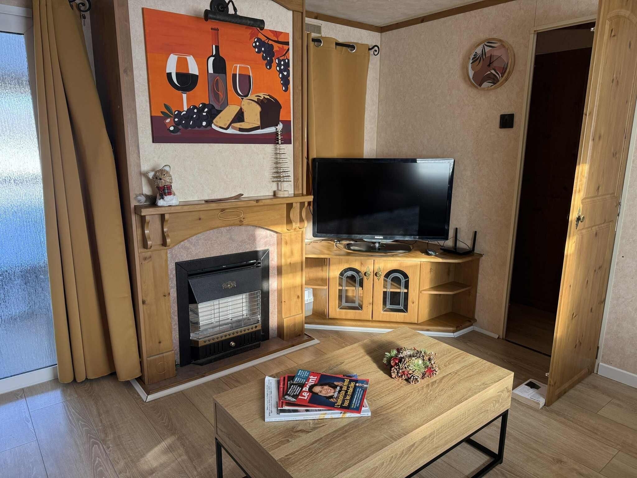 Un salon chaleureux avec une cheminée, un téléviseur et un magazine posé sur la table.