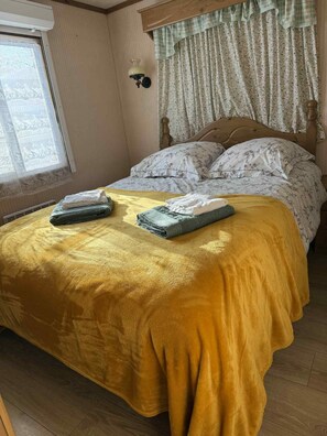 A room with a bed, a window with curtains, and a lamp.