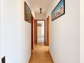 A hallway with wooden flooring, white walls, and framed artwork. - 2BR Tamarán House - Central & Quiet LPGC (Las Palmas de Gran Canaria)