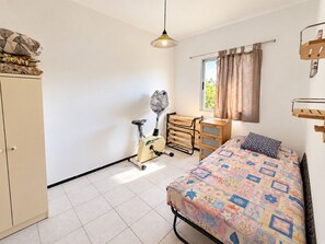 A bedroom with a bed, a wardrobe, a desk, a chair, a window with curtains, and a hanging light fixture. - 2BR Tamarán House - Central & Quiet LPGC (Las Palmas de Gran Canaria)