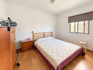 A bedroom with a wooden bed, a nightstand, a wardrobe, and a window with blinds. - 2BR Tamarán House - Central & Quiet LPGC (Las Palmas de Gran Canaria)