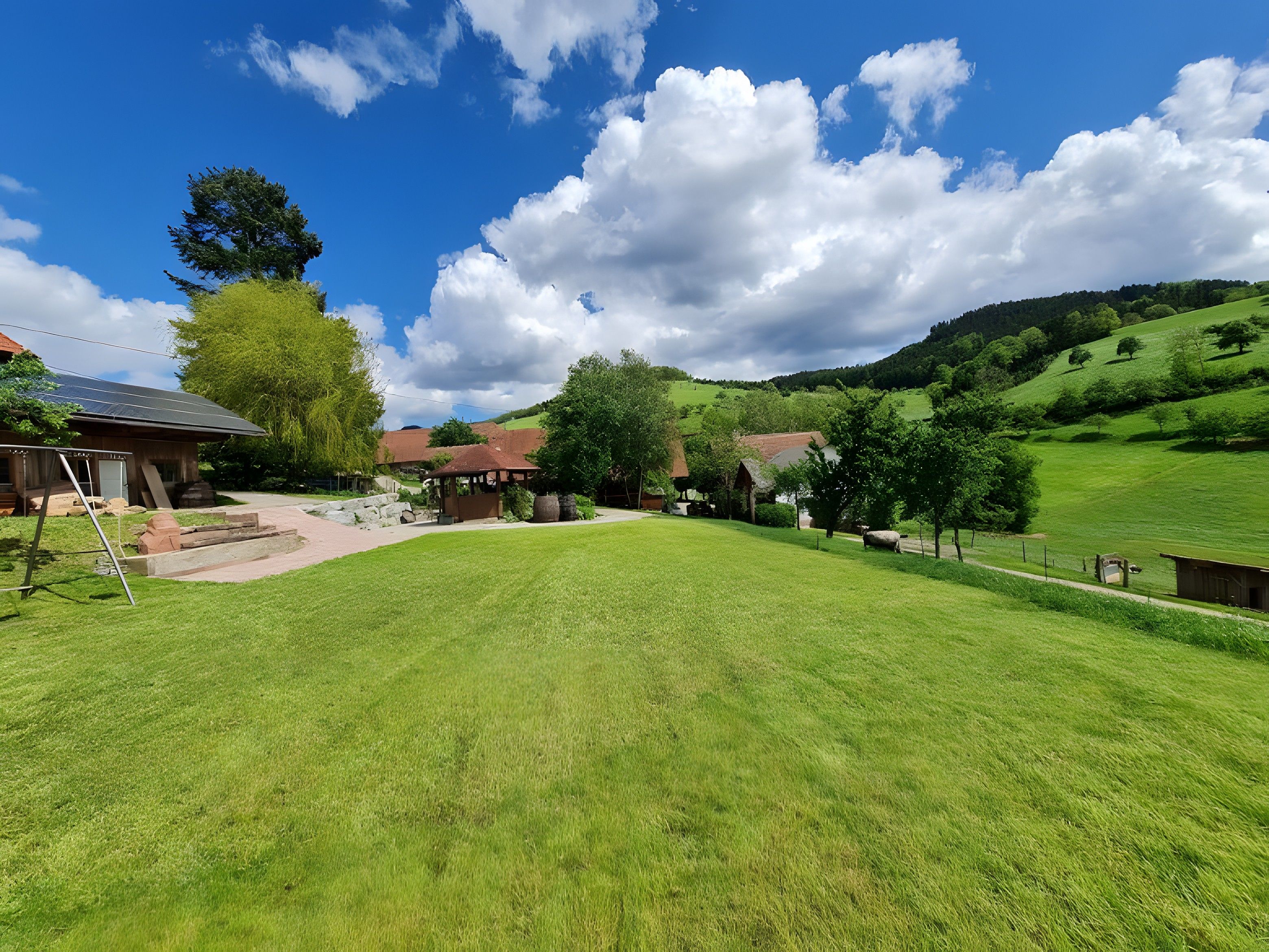 Ländliche Landschaft mit einer Wiese, einer Holzhütte und einem Hügel im Hintergrund.