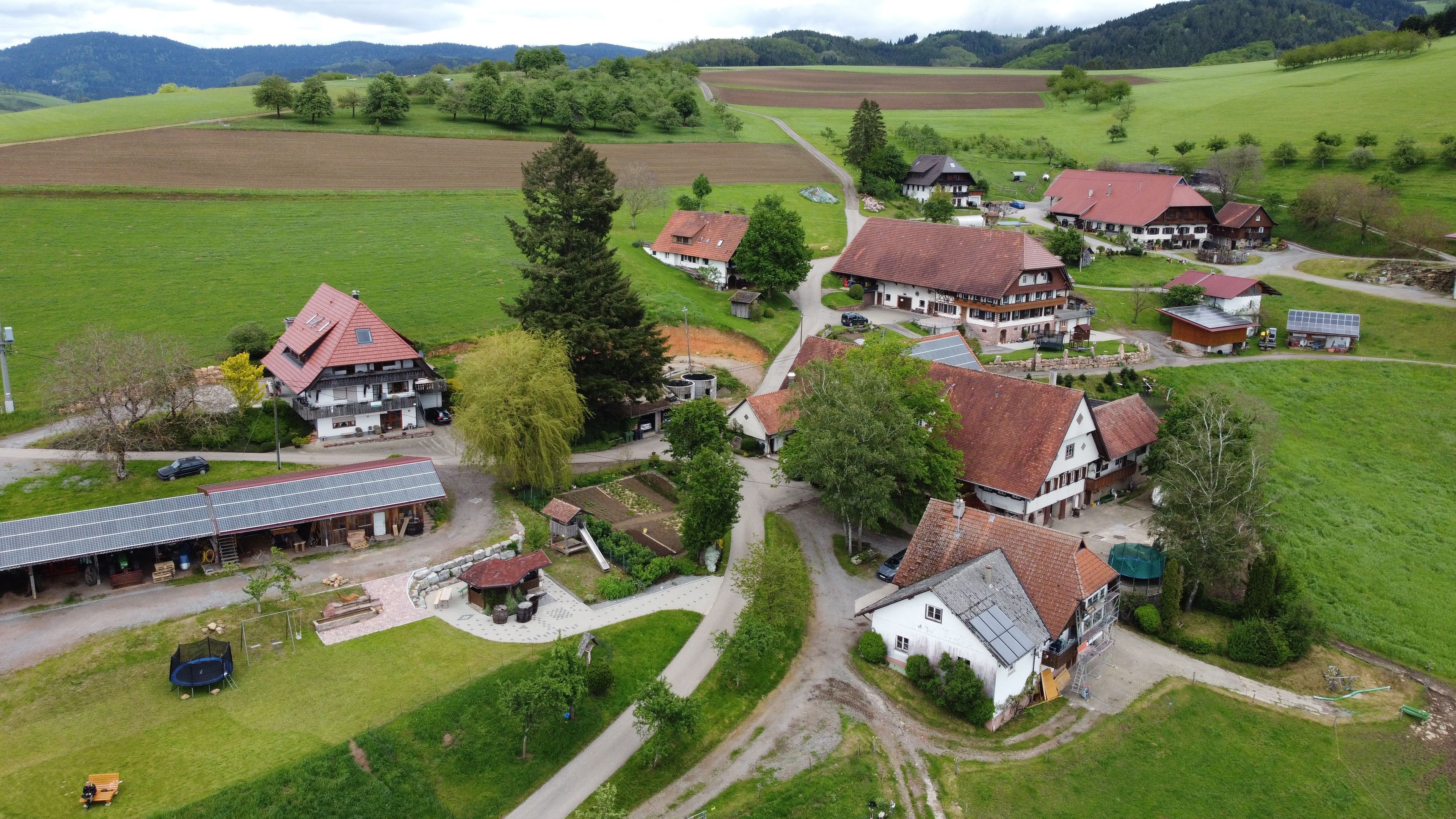 Ein ländliches Dorf mit traditionellen Häusern, einem Gemeinschaftshaus und einer Solaranlage.