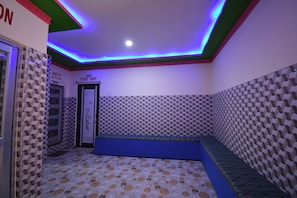 A bathroom with a patterned floor and walls, a bench, and a door labeled 'BATH ROOM'. - Hotel O Gloria Inn (Agartala)