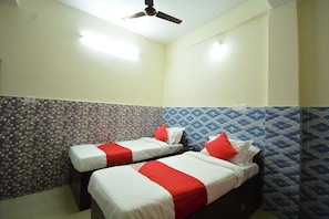 Una habitació d'hotel amb dos llits, un ventilador de sostre i parets amb un disseny decoratiu.